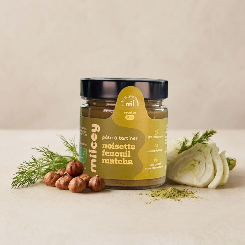Pot de pâte à tartiner bio MIICEY Noisette, fenouil et matcha, entouré de noisettes, de fenouil frais et de matcha en poudre.